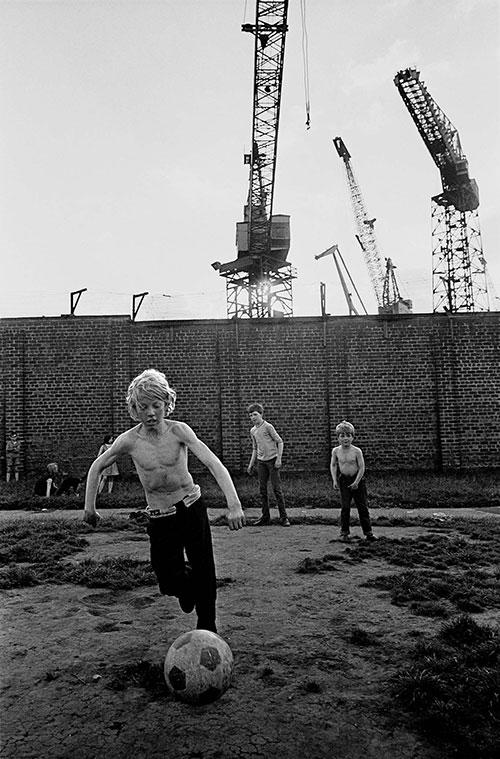 Boy playing football by the Govan shipyards, Glasgow  (1970)