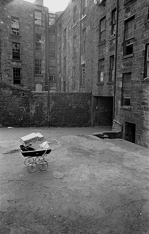 Pram and baby left out in a Maryhill tenement courtyard, Glasgow  (1971)