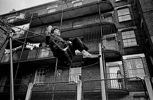 Boy swinging by a Lambeth tenement London  (1969)