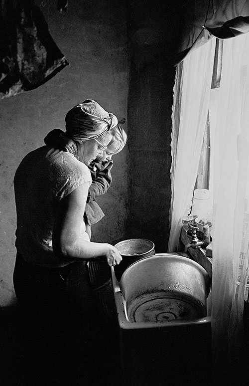 Mrs T and her baby at the sink in their Sheffield home,  (1969)