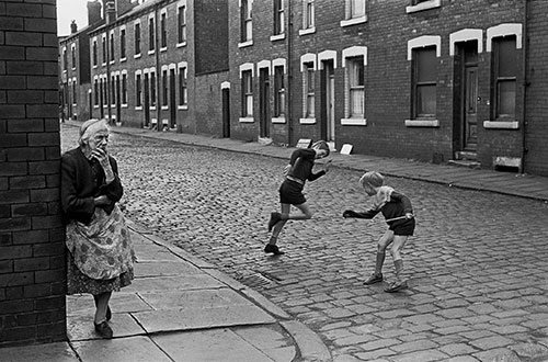 Elderly lady and children at the corner of a street of back to backs Leeds  (1970)