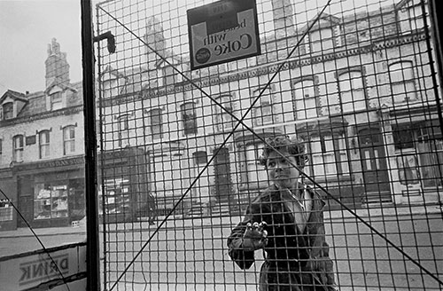 Child looks through the security wire in a Toxteth shop, Liverpool  (1969)